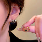 Silver twisted faux double piercing hoop earring on ear, gold version held in hand
