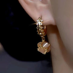 Model showcasing the dangle and style of the 14K Gold-Plated Coffee-Colored Cat's Eye Ball Earrings