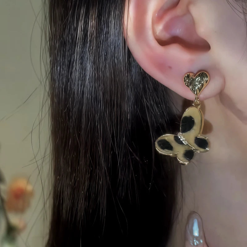 Model showcasing the dangle and style of the 14K Gold-Pated Leopard Print Butterfly Heart Earrings