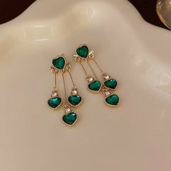 Model showcasing the dangle and style of the 14K Gold-Pated Zircon Green Heart Tassel Earrings