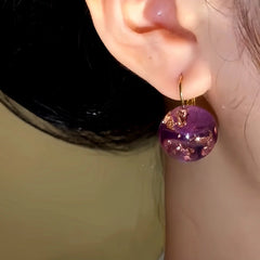 Model showcasing the dangle and style of the 14K Gold-Plated Amber Transparent Ball Earrings