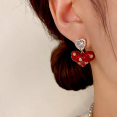 Model showcasing the dangle and style of the 14K Gold-Plated Ankola Red Diamond Heart Earrings
