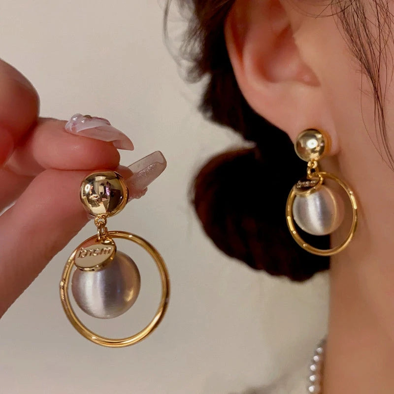 Model showcasing the dangle and style of the 14K Gold-Plated Ball Hoop Earrings