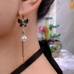 Model showcasing the dangle and style of the 14K Gold-Plated Black Butterfly Pearl Tassel Ear Hook Earrings