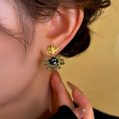 Model showcasing the dangle and style of the 14K Gold-Plated Black Diamond Ginkgo Leaf Pendant Tassel Earrings