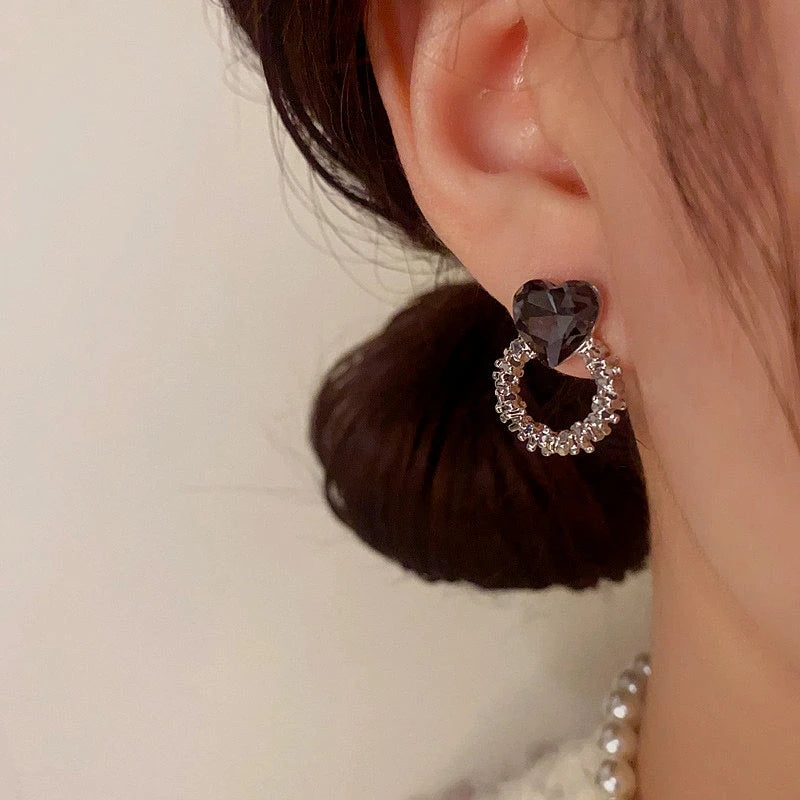 Model showcasing the dangle and style of the 14K Gold-Plated Black Diamond Heart Hoop Earrings