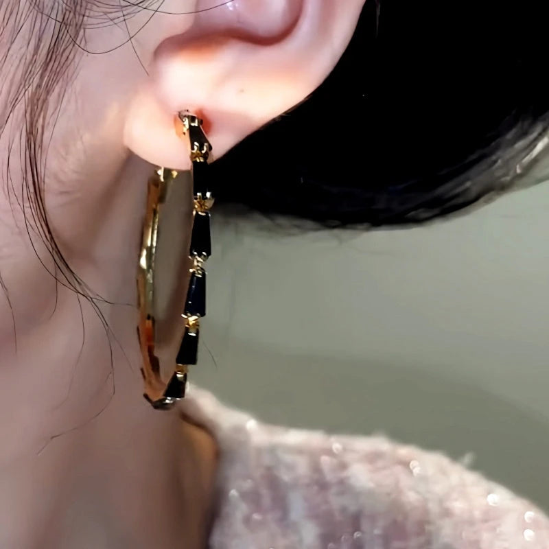 Model showcasing the dangle and style of the 14K Gold-Plated Black Zircon Hoop Earrings