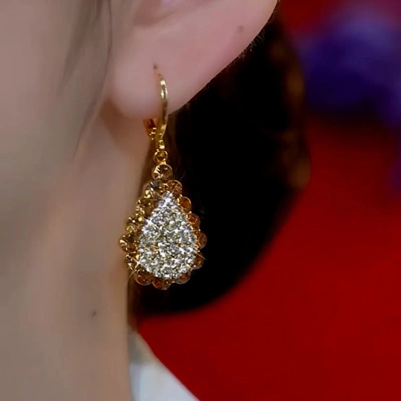 Model showcasing the dangle and style of the 14K Gold-Plated Bling Diamond Earrings