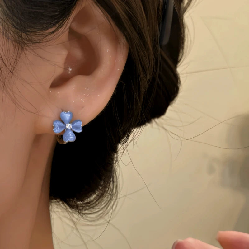 Model showcasing the dangle and style of the 14K Gold-Plated Blue Four-Leaf Clover Earrings