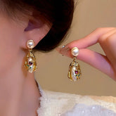 Vintage gold pearl rose drop earrings, one worn on ear one held for display