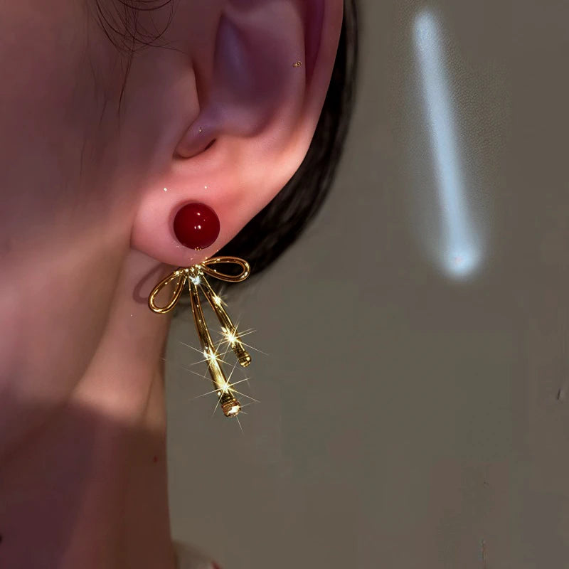 Model showcasing the dangle and style of the 14K Gold-Plated Bow Pearl Earrings