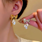 Gold and silver bow baroque pearl drop earrings: gold worn on ear, silver held in hand