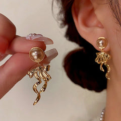Model showcasing the dangle and style of the 14K Gold-Plated Bow Tassel Earrings