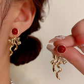 Red round bead gold twisted ribbon bow drop dangle earrings, worn and held