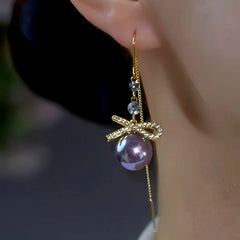 Gold bow purple pearl dangle earring with side chain detail on ear
