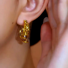 Shiny gold huggie hoop earring on female ear, side close view