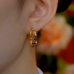 Model showcasing the dangle and style of the 14K Gold-Plated Brown Diamond Hoop Earrings