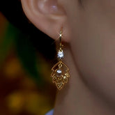 Gold leaf pearl drop huggie hoop earring with cubic zirconia on woman's right ear