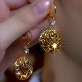Sparkly gold moon rose crystal dangle earrings, pair held in hand