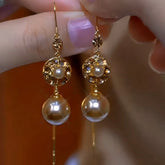 Pair of vintage gold pearl crystal drop dangle earrings held in hand