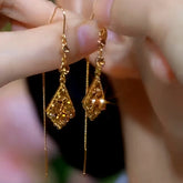 Pair of gold teardrop crystal long threader dangle earrings held between fingers