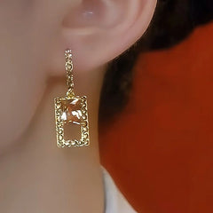 Textured gold champagne crystal square drop earring worn on earlobe
