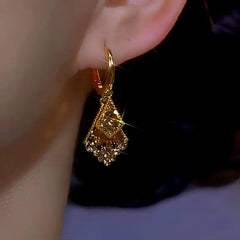 Side view of gold layered geometric sparkly drop earring on ear