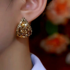 Angled close-up of gold teardrop pave stud earring on ear