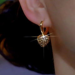 Model showcasing the dangle and style of the 14K Gold-Plated Brown Zircon Diamond Heart Earrings