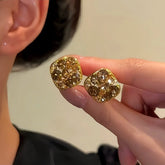 Pair of gold square champagne crystal stud earrings held between fingers