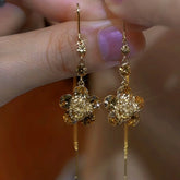Gold crystal flower long tassel dangle drop earrings pair held in hand