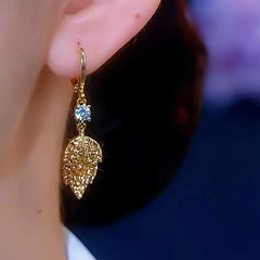 Gold textured leaf crystal dangle earring worn on ear, side view