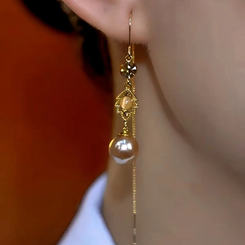 Model showcasing the dangle and style of the 14K Gold-Plated Brown Zircon Leaf Pearl Threader Tassel Earrings