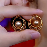 Hand holding pair of vintage gold champagne pearl crescent hoop earrings