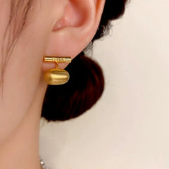 Model showcasing the dangle and style of the 14K Gold-Plated Brushed Bean Earrings