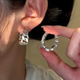 Chunky silver curb chain hoop earring worn on ear, matching hoop held beside it