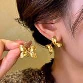 Women's gold butterfly front-back earrings, one held in hand, one worn on ear