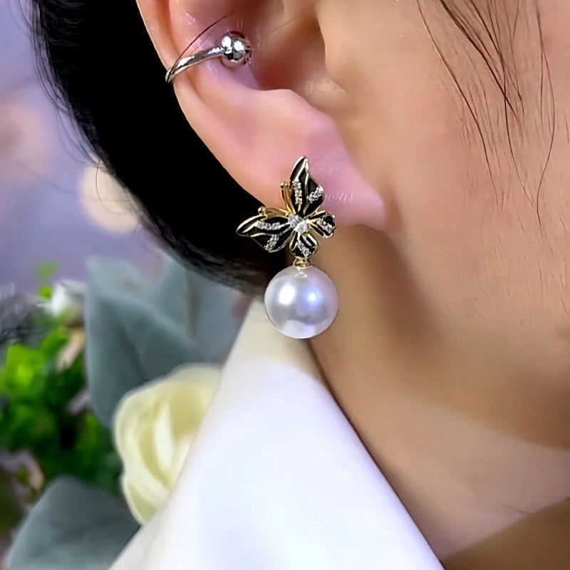 Model showcasing the dangle and style of the 14K Gold-Plated Butterfly Pearl Earrings