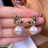 Gold black enamel crystal butterfly pearl drop earrings pair, hand-held close-up