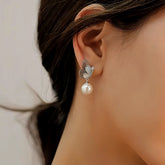 Women's silver butterfly pearl drop earring worn on ear, side close-up