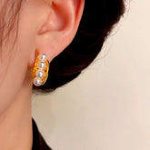 Women's gold pearl half-hoop earring on right ear, close-up shot
