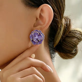 Woman wearing purple enamel camellia flower stud earrings
