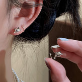 Hand holding cute silver cat half hoop earring next to ear wearing matching style