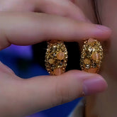 Hand holding pair of vintage gold amber cat's eye crystal oval hoop earrings