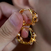 Gold champagne crystal opal bead huggie hoop earrings held between fingers