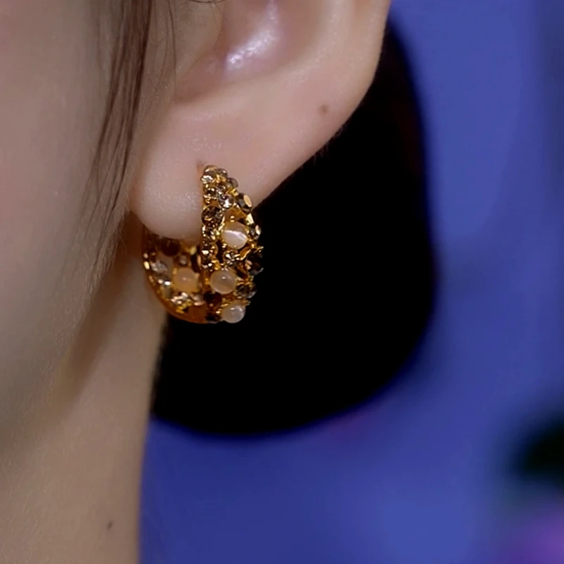 Model showcasing the dangle and style of the 14K Gold-Plated Cat's Eye Brown Zircon Hoop Earrings