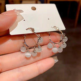 Silver cat eye bead dangle hoop earrings on white jewelry display card