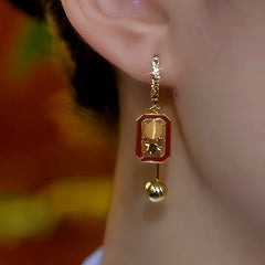 Red enamel gold rectangular bell dangle earring worn on right ear