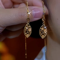 Pair of vintage gold filigree teardrop dangle earrings with cat's eye beads, held in hand