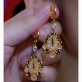 Pair of Gold Teardrop Champagne Crystal Beaded Drop Hoop Earrings Held in Hand